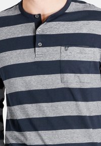 Grau und marineblau gestreiftes Langarm-Henley-Shirt mit drei Knöpfen, einer Brusttasche und einer weichen Baumwollstruktur.