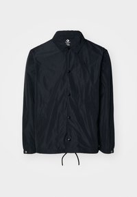Veste coupe-vent marine fabriquée en tissu léger, dotée d'un col, de boutons-pression à l'avant, de poches latérales et d'ourlet réglable à cordon.