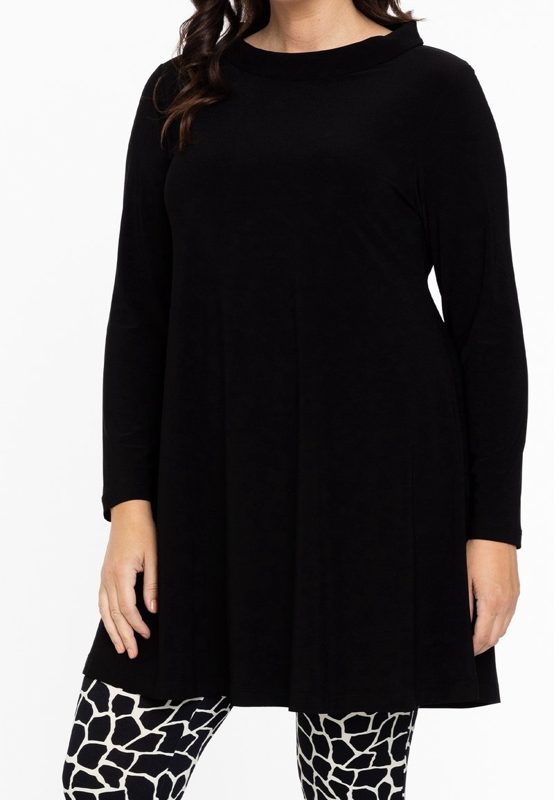 Schwarze Langarm-Tunika mit Rundhalsausschnitt, aus weichem Stoff, kombiniert mit leggings in Weiß und Schwarz mit einem Giraffendruck.
