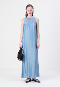 Light blue sleeveless maxi dress with a smooth texture, paired with a black textured handbag and flat black shoes.