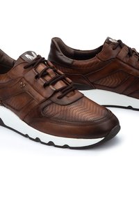 Zapatillas de cuero marrón con paneles texturizados, que cuentan con una mediasuela blanca, cordones redondos y un discreto logotipo en la lengüeta.