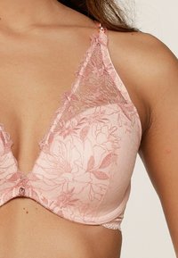 Zacht roze bh met kanten details, bloemenpatroon, driehoekige vorm en verstelbare bandjes. Kenmerkt een decoratieve versiering aan de voorkant.