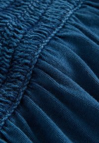 Tissu tricoté d'un bleu profond avec des points texturés et des sections froncées, présentant une surface douce et lisse.