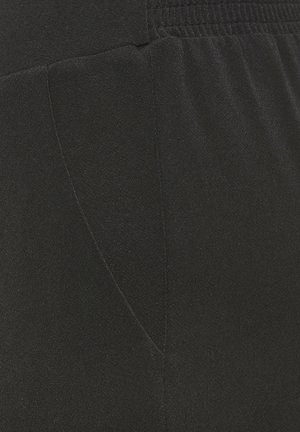 Nahaufnahme von schwarzem Stoff mit elastischem Bund und sichtbaren Nähten, die Textur- und Nahtdetails eines Kleidungsstücks zeigen.