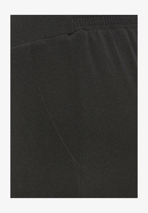 Close-up of black fabric with elastic waistband and visible stitching, showing texture and seam details on a garment.