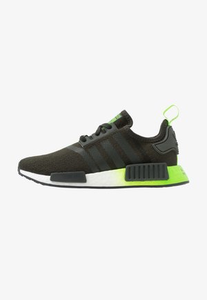 Baskets Adidas NMD noires avec trois bandes, semelle intermédiaire blanche et accents vert néon au talon, présentées en profil sur fond blanc.