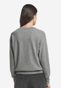Grauer Pullover mit langen Ärmeln und Rundhalsausschnitt, ausgestattet mit gerippten Bündchen und Saum. Weicher Stoff, lässige Passform und minimalistisches Design.
