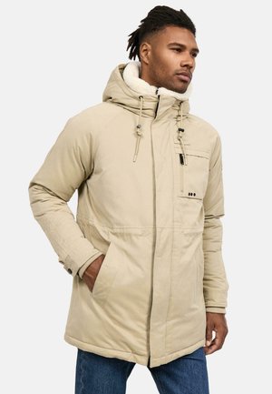 Beige polstret jakke med hætte og fleecefor. Har frontlynlås, lomme og justerbare snore for en sikker pasform.