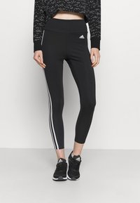 Svarta atletiska leggings med hög midja och vita sidostrimlor. Tillverkade av elastiskt material, designade för aktiv användning.