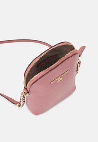 Pink leather crossbody bag with a golden zipper, featuring a gold logo and chain accent on the strap. Interior has a lining with compartments.