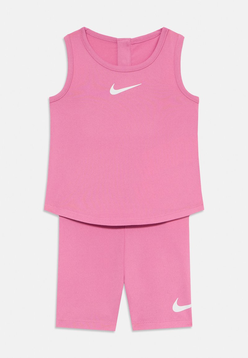 Rózsaszín sportos szett, amely egy ujjatlan, kerek nyakú felsőből és hozzá illő rövidnadrágból áll. Mindkettőn fehér Nike logó található. Sima, rugalmas anyag.