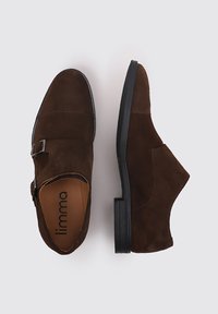 Zapatos de ante marrón con un diseño elegante, que presentan un hebilla lateral y una punta redonda, montados sobre una suela de goma negra.