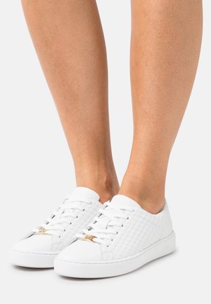 Witte sneakers van gestructureerd materiaal met diamantpatronen, met een gouden accent op de veters en een platte rubberen zool.