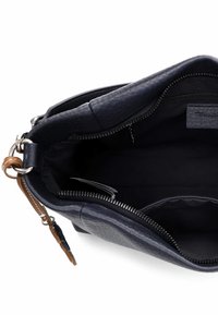 Marineblå læderhåndtaske med tekstureret overflade, lynlåsåbning og indvendig lomme, der viser en rummelig inderside foret med sort stof.