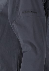 Mörkgrå jacka med en slät yta, som har en präglad "ENDURANCE"-logotyp på vänster ärm. Materialet verkar vara lätt och vattenavvisande.