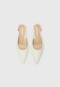 Korkean kantapään slingback-kengät teräväkärkisinä kiiltävässä off-white-materiaalissa. Varustettu kapealla hihnalla, jossa on kultasävyinen solki, ja sileällä beigellä pohjallisella.