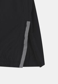 Schwarze Jacke mit einem grauen Reißverschluss und Nahtdetails am unteren Rand. Der Stoff weist eine dezente Textur auf, und der Schnitt ist schlank für eine taillierte Optik.