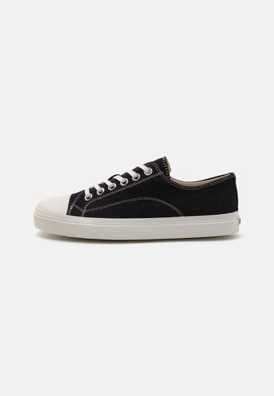 Sneaker nera in tela con punta e suola in gomma bianca, dotata di lacci bianchi e cuciture a contrasto. Design a profilo basso.