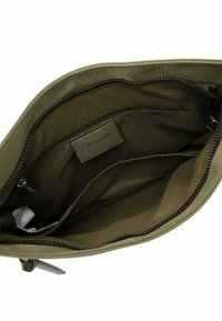 Olive green textile bag interior with smooth lining, zippered pocket, and a small label. Features sturdy zipper and spacious compartments.
