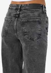 Svarta denimjeans med en urtvättad finish. Funktioner inkluderar två bakfickor, en läderetikett vid midjan och en klassisk rak passform.