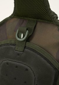 Black mesh harness with dark green accents, featuring a rounded attachment loop and padded sections for comfort and support.