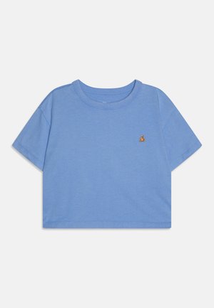 T-shirt cropped bleu en tissu doux, avec des manches courtes et un col rond. Comprend un petit accent brodé sur la poitrine.