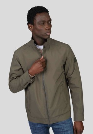 Veste zippée vert olive avec col montant, poignets côtelés et poches latérales. Tissu lisse et léger avec des détails de couture subtils.