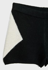 Shorts en maille noire avec un motif triangulaire blanc sur le côté et une taille élastique côtelée.