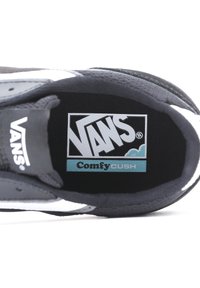 Sneakers med överdel av svart tyg, vita sidosträck och en mjuk svart innersula med en blå "ComfyCUSH"-logotyp.