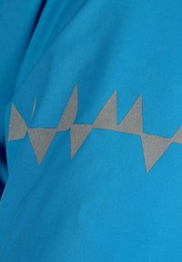 Blått tyg med en horisontell rad av reflekterande silvertrianglar som bildar ett zickzackmönster över det.