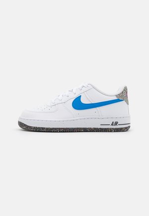 Białe sneakersy Nike z niebieskim logo, teksturowana cholewka i wielokolorowa, nakrapiana podeszwa. Klasyczny design na sznurówki z detalem "AIR" z boku.