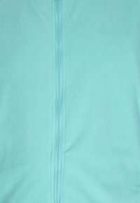 Giacca in pile turchese con una texture liscia, dotata di chiusura centrale con zip e senza motivi o decorazioni visibili.