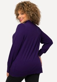 Maglione viola a maniche lunghe con una vestibilità rilassata, orlo a coste e maniche leggermente affusolate. Tessuto liscio con una leggera lucentezza.