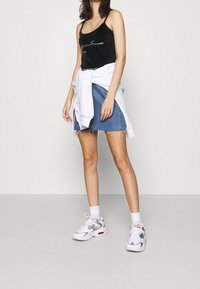 Svart sammetstopp med rhinestones, denimminikjol med fransar, och vita sneakers med silverdetaljer.