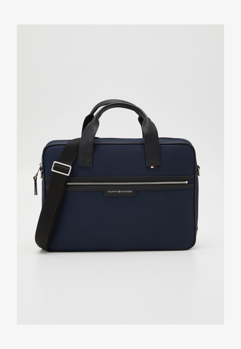 Marineblauwe laptop tas van stof met zwarte leren accenten, dubbele handgrepen bovenaan, een afneembare schouderband en een voorzak met rits. Voorzien van een logo-label.