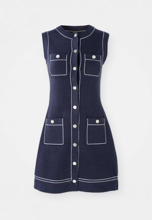 Laivastonsininen hihaton mekko, jossa on pyöreä pääntie, etupainatus, kaksi rintataskua ja kontrastivalkoiset ompelut yksityiskohdat.