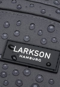 Borsa in tessuto grigio con gocce d'acqua, dotata di un'etichetta rettangolare nera con "LARKSON HAMBURG" in bianco. Superficie testurizzata, chiusura a zip.