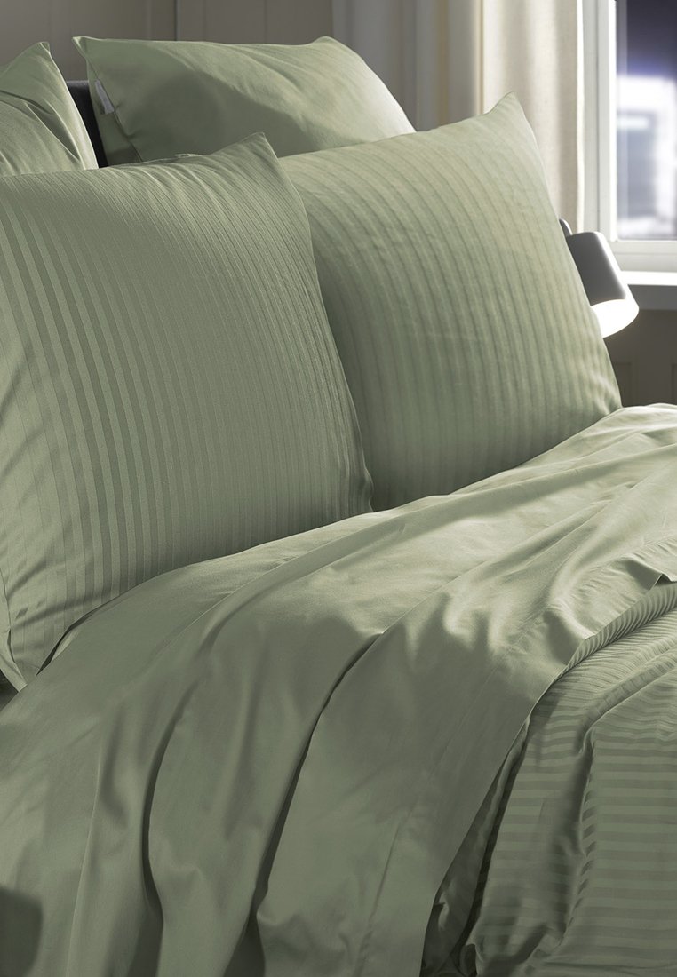 Juego de cama de rayas verdes con tejido texturizado, que incluye dos fundas de almohada a juego y una funda nórdica suave, dispuestos ordenadamente sobre una cama.