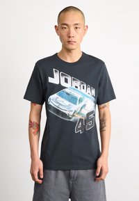 Camiseta de algodón negra con un gráfico de un coche y el texto "JORDAN 45" en blanco. Manga corta, escote redondo, corte casual.