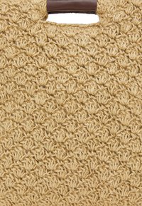 Vævet stråtask i naturbeige med et struktureret mønster, der har en glat brun håndtag og et åbent design for nem adgang.
