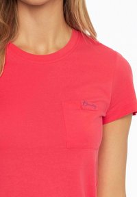Coral pink cotton T-shirt with a crew neck, short sleeves, and a small front pocket featuring blue stitching of the word "Beauty."