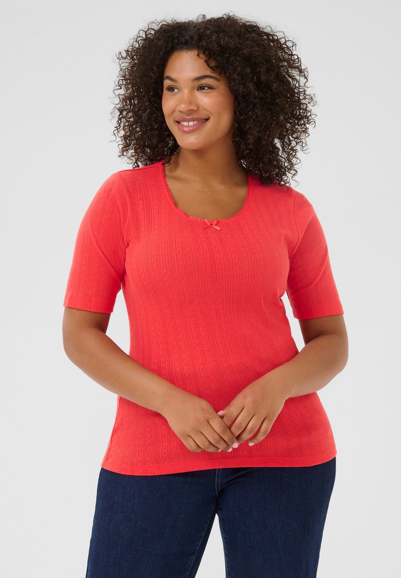 T-shirt en maille corail à manches courtes, avec un décolleté en forme de scoop et un détail de nœud décoratif à l'avant. Présente un motif texturé sur l'ensemble.
