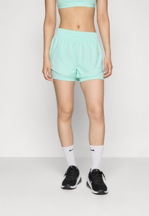 Pantaloni sportivi verde menta con elastico in vita, caratterizzati da un piccolo logo sul lato. Indossati con scarpe da ginnastica nere e calzini bianchi a crew.