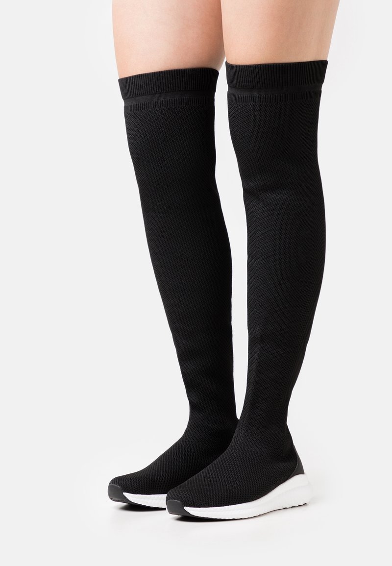 Calcetines negros hasta la rodilla con diseño de tejido texturizado, puño acanalado y suela integrada en blanco y negro para mayor comodidad y estilo.