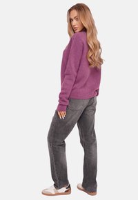 Purple oversized knit sweater with long sleeves, paired with gray straight-leg jeans and white sneakers featuring a patterned accent.