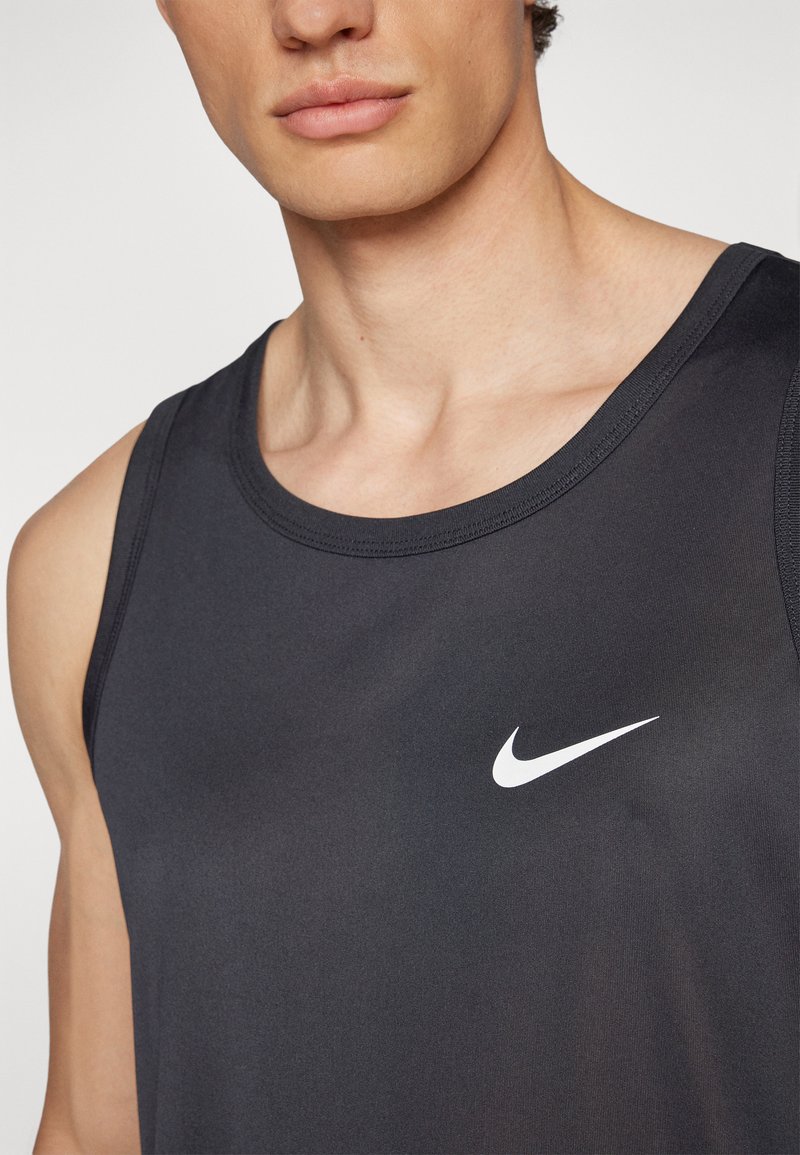 Top deportivo negro de tirantes, fabricado con un tejido ligero. Cuenta con un escote redondeado y un prominente logo de Nike en blanco en el pecho.
