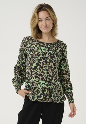 Blouse imprimé léopard en vert, noir et beige. Dotée de longues manches bouffantes avec des poignets élastiques et d'un col rond. Tissu léger.