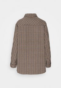 Chaqueta camisa de cuadros marrones y beige con cuello clásico, mangas largas y un ajuste relajado. Tejido con textura y patrones contrastantes.