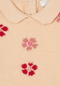 Beige gebreide top met een geknoopte kraag, versierd met rode en roze bloemenpatronen overal. Zachte textuur met knoopsluiting.