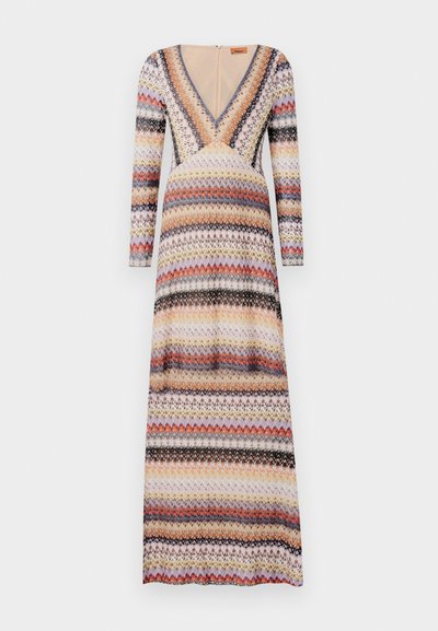 Maxi suknelė su ilgomis rankovėmis, V formos kaklu ir daugiamačiu zigzago raštu raudonos, oranžinės, violetinės ir juodos spalvų ant šviesaus fono.